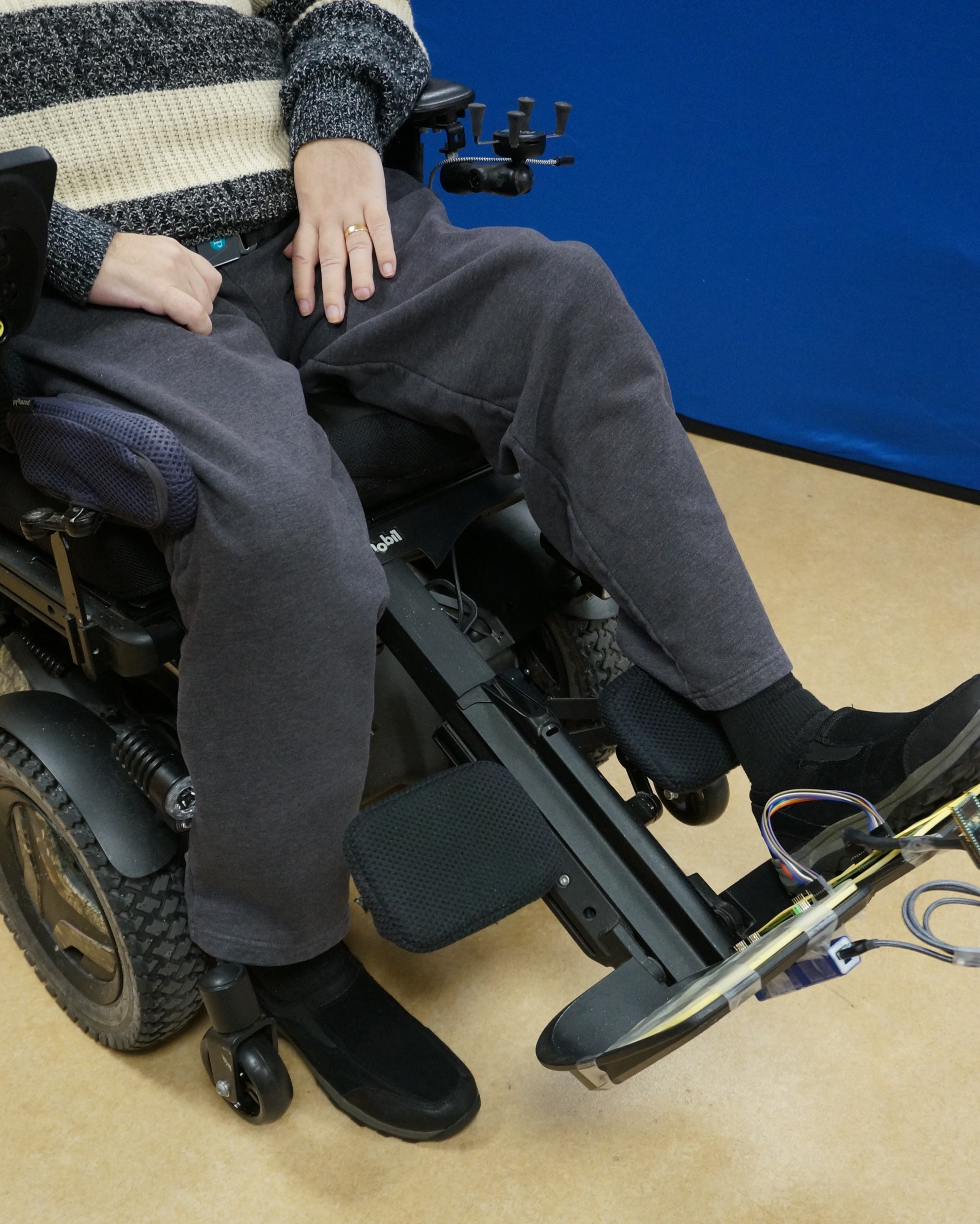 A person in a power wheelchair with one foot off the footplate